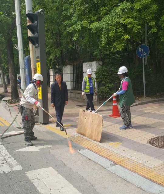 ▲ 횡단보도 화강암 경계석 (물갈기 면)의 '버너구이' 시범 시공을 하고 있는 장면     © 사진 = 원용의의원 제공